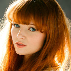 Headshot of actor and Hunger Games start Stef Dawson gazing gently into the camera.