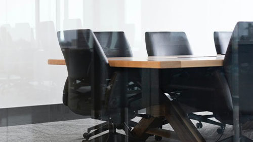 Image of an empty conference room desk taken through glass