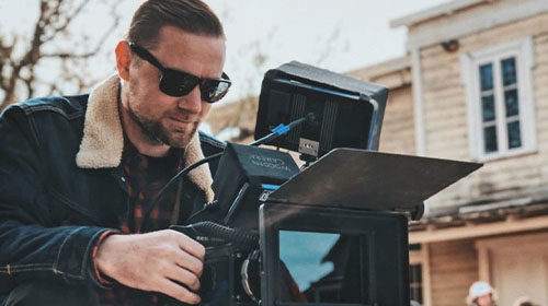 image of a man wearing sunglasses operating a cinema camera