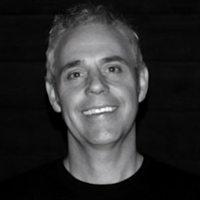 Headshot of Darren Ashton in black and white smiling at the camera.